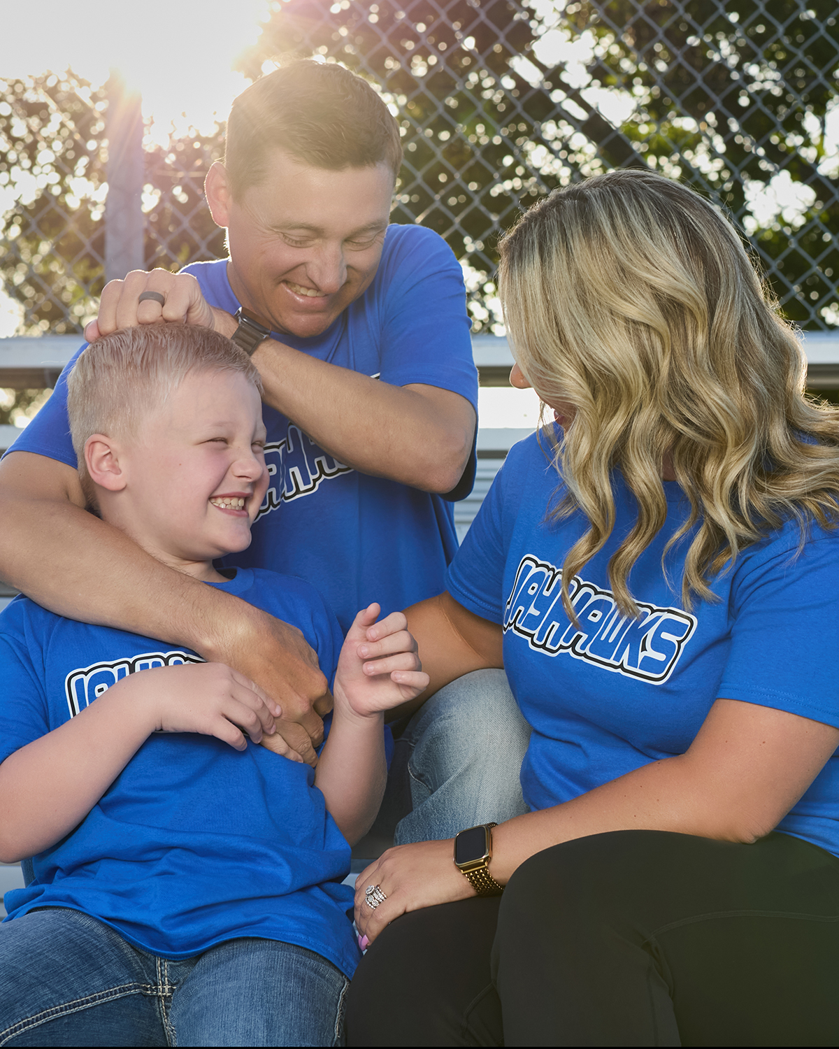 A family in matching Jayhawks spirit wear sharing a joyful moment in the stands.